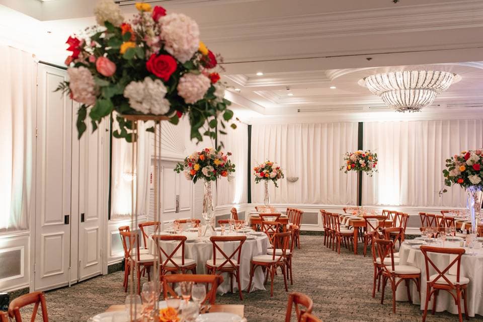 The event hall in white drapery with tall, colorful flower arrangements